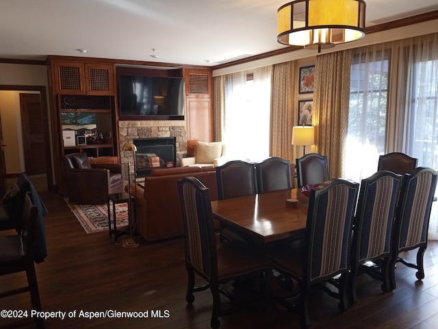 dining room featuring dark hardwood / wood-style flooring, crown molding, and a fireplace