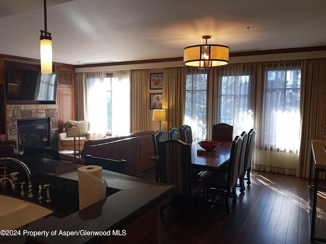 dining space featuring a fireplace, dark wood-type flooring, ornamental molding, and sink