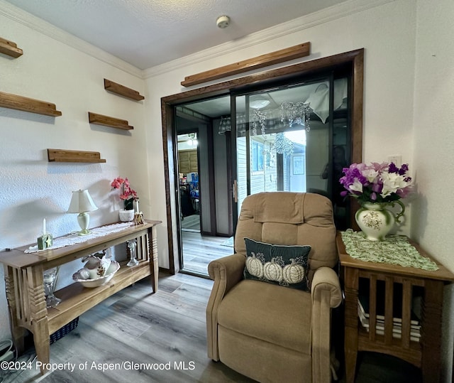 sitting room with wood-type flooring, a textured ceiling, a wealth of natural light, and crown molding