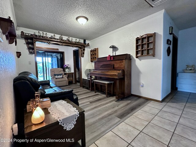 living room featuring light tile patterned floors, a textured ceiling, and ornamental molding