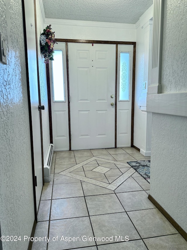 tiled foyer entrance featuring a textured ceiling, baseboard heating, and crown molding