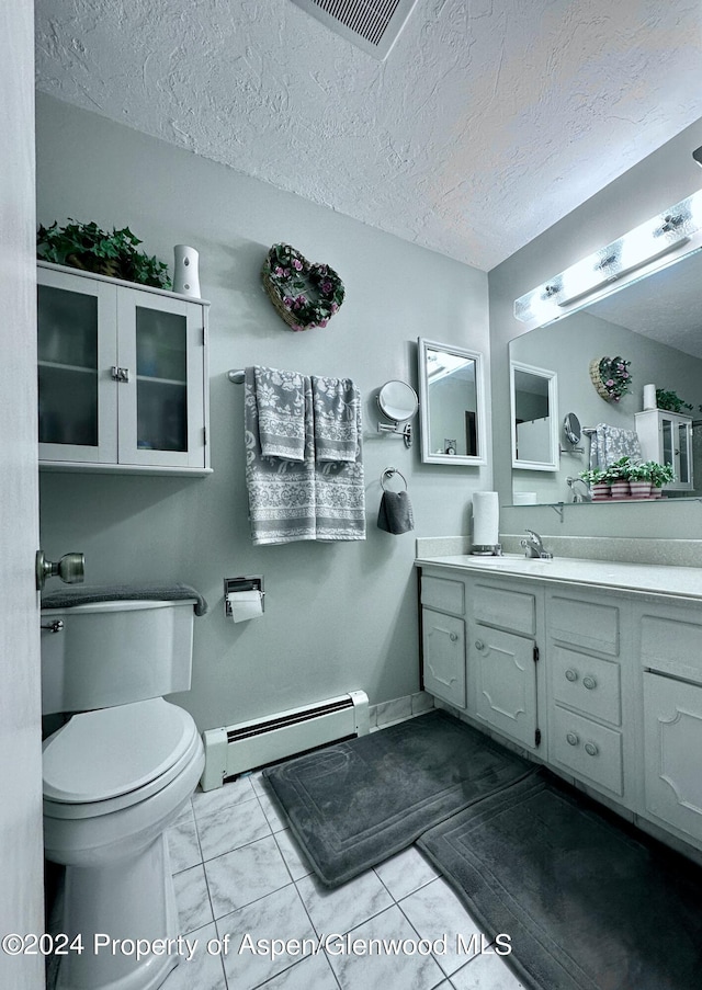 bathroom featuring tile patterned floors, vanity, a textured ceiling, a baseboard heating unit, and toilet