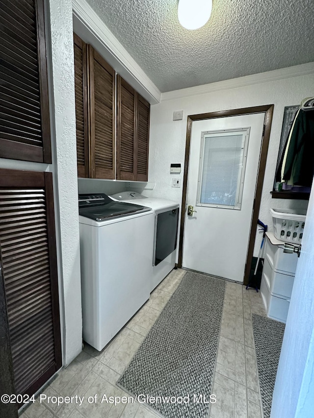 laundry area with cabinets, a textured ceiling, ornamental molding, and washing machine and clothes dryer