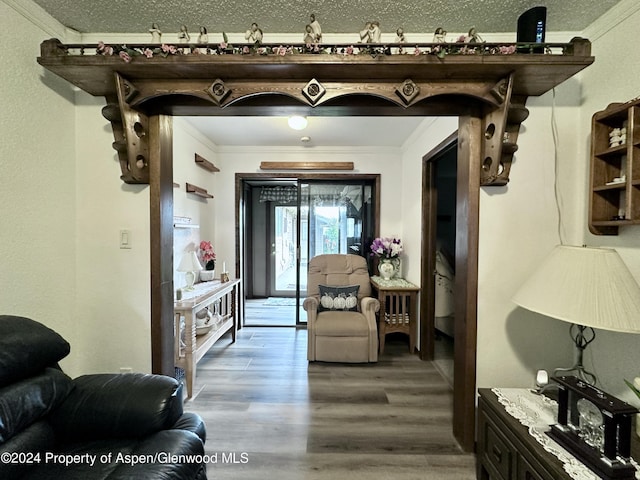 interior space featuring hardwood / wood-style flooring, crown molding, and a textured ceiling