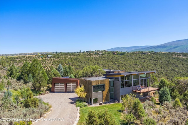 exterior space with an outbuilding, a mountain view, a garage, driveway, and a forest view