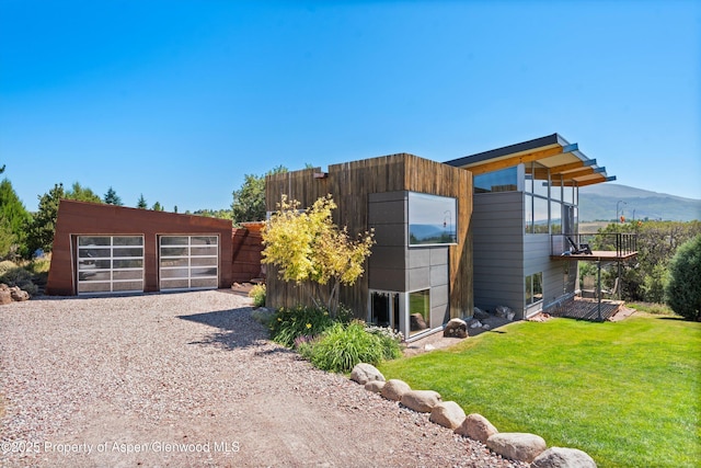 view of property exterior featuring a yard, a detached garage, a mountain view, and an outdoor structure