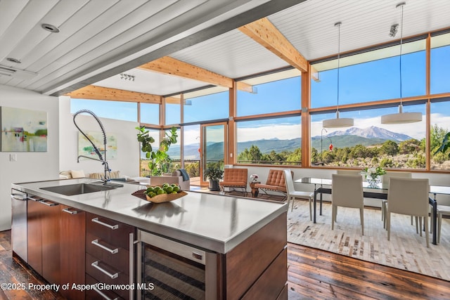 kitchen with dark wood-style floors, beverage cooler, a center island with sink, and a mountain view