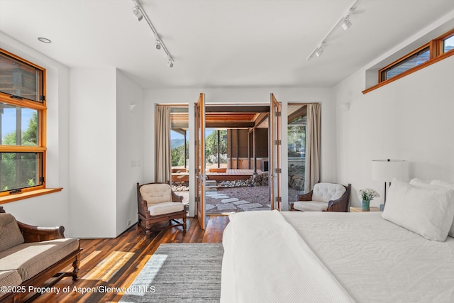 bedroom featuring access to exterior, rail lighting, and dark wood finished floors