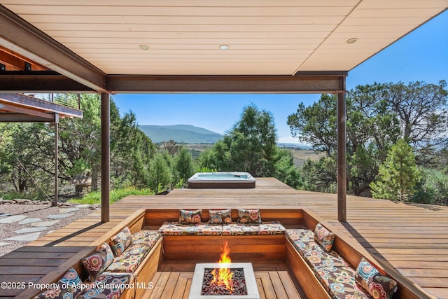 exterior space with a deck with mountain view, hot tub deck surround, and a fire pit