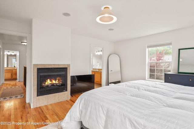 121 Ranch Creek Ln, Carbondale, CO 81623 - bedroom with light wood-style flooring, a tiled fireplace, and ensuite bath
