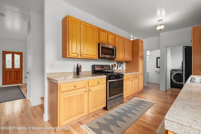 121 Ranch Creek Ln, Carbondale, CO 81623 - kitchen featuring stainless steel appliances, washer / dryer, light wood-type flooring, baseboards, and tile counters