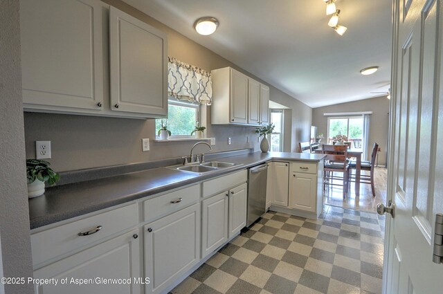 222 Creek Ct, Rifle, CO 81650 - kitchen featuring stainless steel dishwasher, light flooring, a peninsula, lofted ceiling, and white cabinets