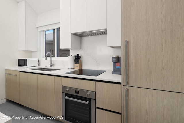 211 W Main St, Aspen, CO 81611 - kitchen featuring stainless steel oven, a sink, white microwave, light countertops, and black electric cooktop