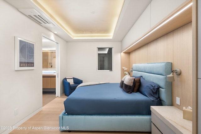 211 W Main St, Aspen, CO 81611 - bedroom featuring a raised ceiling, light wood-style flooring, connected bathroom, and baseboards