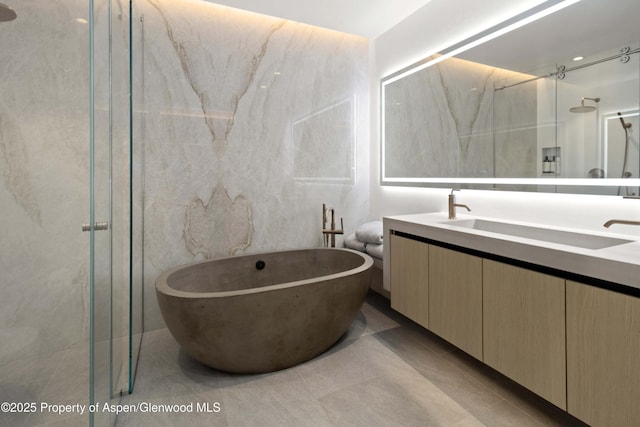 211 W Main St, Aspen, CO 81611 - full bathroom featuring double vanity, a freestanding tub, a shower with door, and tile patterned floors