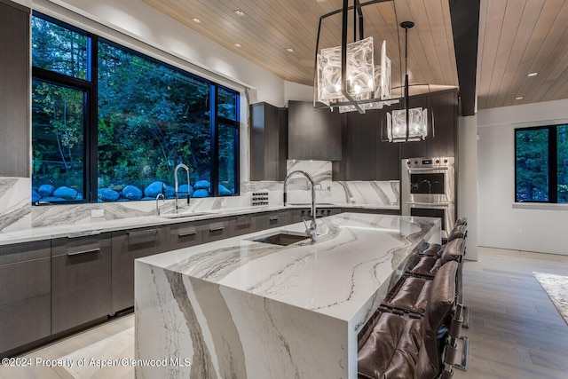 kitchen featuring pendant lighting, a large island, stainless steel double oven, and sink