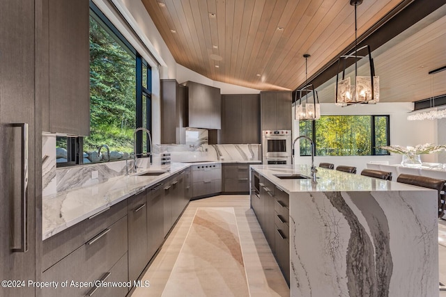 kitchen featuring decorative light fixtures, wooden ceiling, sink, and a large island with sink