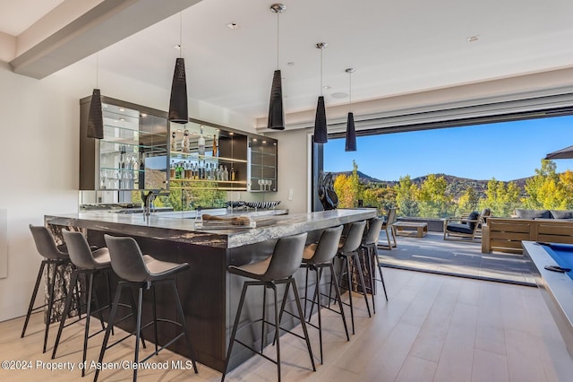 kitchen with hardwood / wood-style floors, a mountain view, dark stone countertops, decorative light fixtures, and a kitchen bar