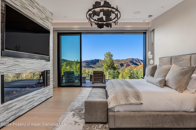 bedroom with a notable chandelier, a mountain view, light hardwood / wood-style floors, and access to exterior