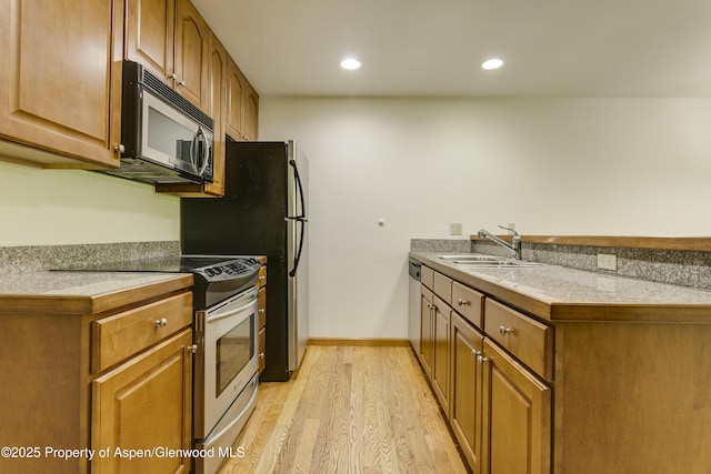201 14th St Unit 300, Glenwood Springs, CO 81601 - kitchen featuring appliances with stainless steel finishes, a sink, light wood-type flooring, a peninsula, and brown cabinets