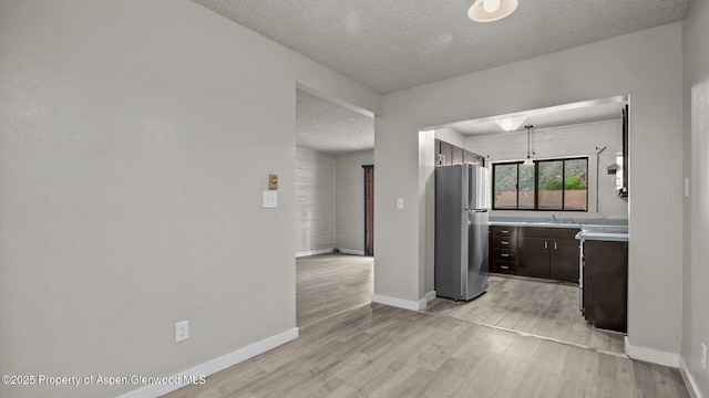 200 S E Ave Unit 111, New Castle, CO 81647 - kitchen with freestanding refrigerator, a textured ceiling, dark brown cabinets, light countertops, and light wood-type flooring