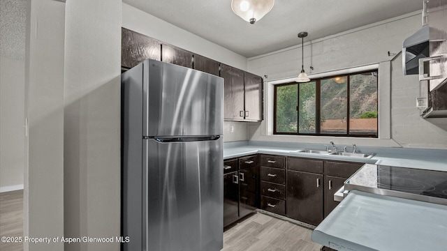 200 S E Ave Unit 111, New Castle, CO 81647 - kitchen with freestanding refrigerator, light wood finished floors, light countertops, and dark brown cabinetry