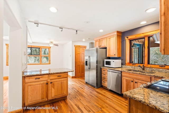 kitchen with appliances with stainless steel finishes, light stone countertops, light wood-style floors, a sink, and recessed lighting