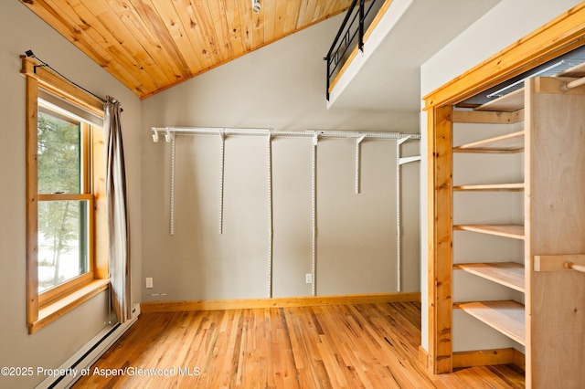 interior space with a baseboard heating unit, lofted ceiling, and light wood-style flooring