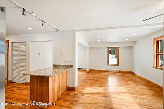 kitchen with a baseboard heating unit, a peninsula, baseboards, light wood-style floors, and track lighting