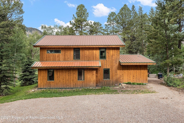 exterior space featuring gravel driveway, a mountain view, and metal roof