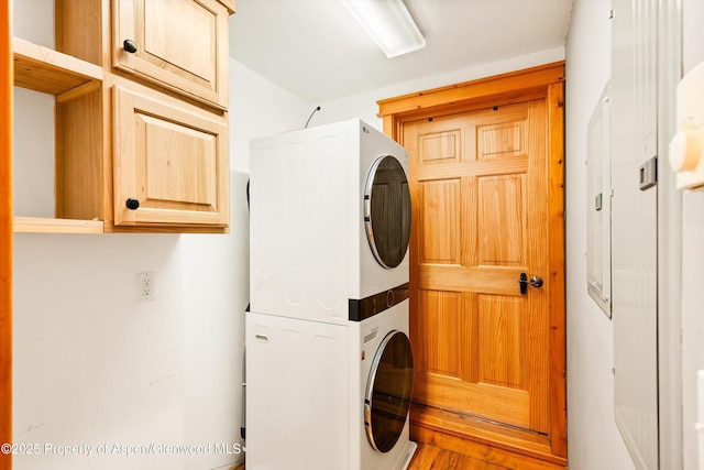 washroom with stacked washer and clothes dryer and cabinet space