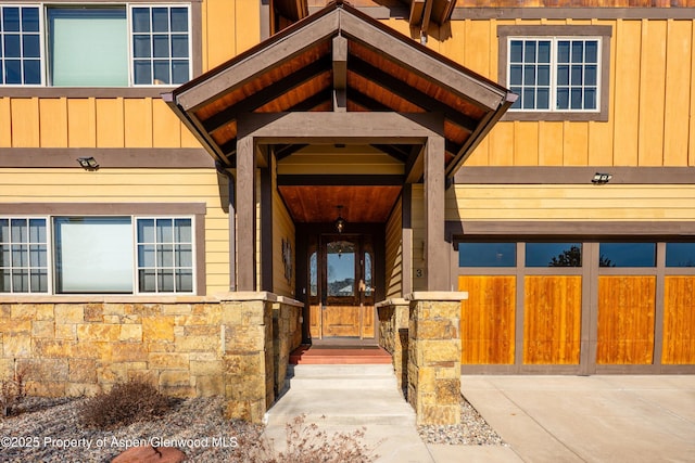 view of exterior entry featuring board and batten siding and stone siding