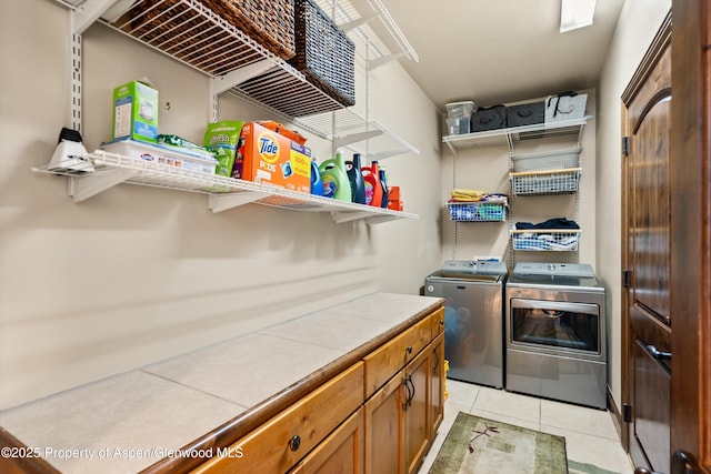 clothes washing area featuring washer and dryer, light tile patterned flooring, and laundry area