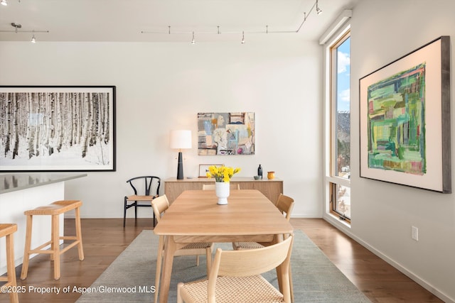 dining room with track lighting, baseboards, and wood finished floors