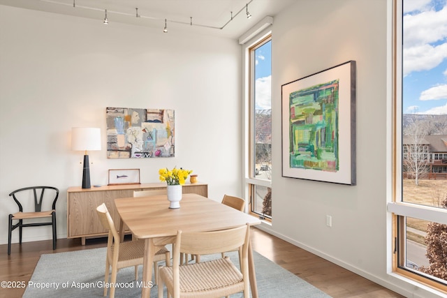 dining space featuring track lighting, baseboards, and wood finished floors