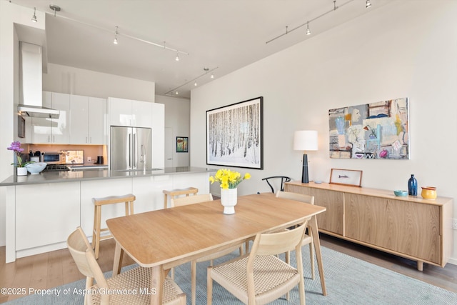 dining space with track lighting and light wood-style floors