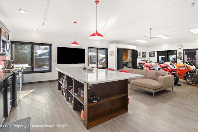 kitchen with ceiling fan, light wood-type flooring, a center island, and decorative light fixtures