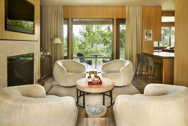 living room featuring a wealth of natural light, wood walls, and hardwood / wood-style floors