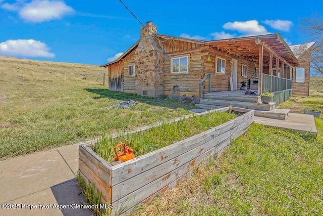 5904 County Road 31, Craig, CO 81625 - view of front facade featuring log siding, a chimney, and a front lawn
