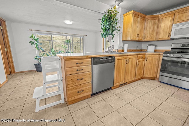 5904 County Road 31, Craig, CO 81625 - kitchen with appliances with stainless steel finishes, a sink, light tile patterned floors, light countertops, and a peninsula