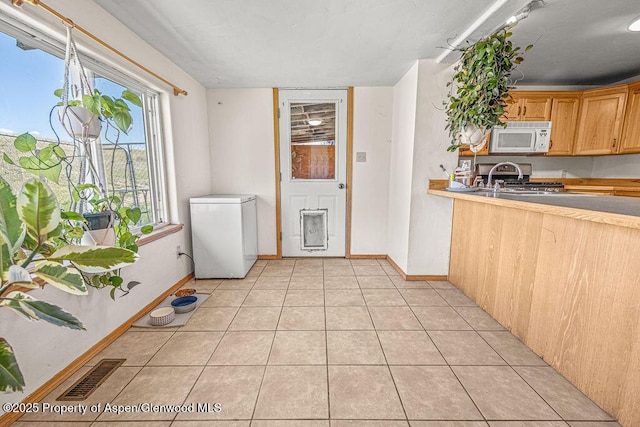 5904 County Road 31, Craig, CO 81625 - kitchen with white microwave, refrigerator, range, light tile patterned floors, and baseboards