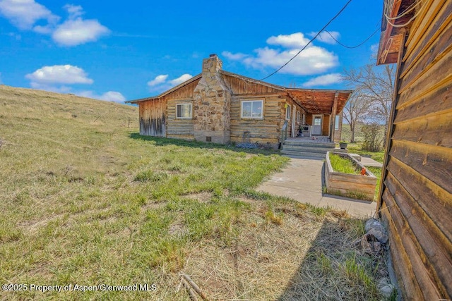 5904 County Road 31, Craig, CO 81625 - view of side of property featuring a chimney, log exterior, and a yard