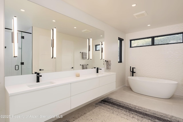 bathroom with double vanity, recessed lighting, a stall shower, and a sink