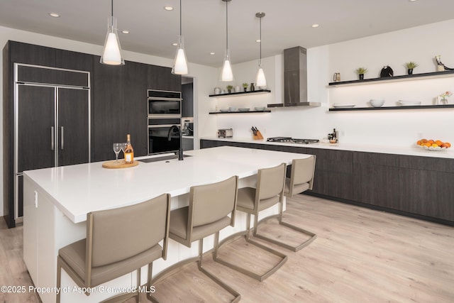 kitchen featuring paneled built in refrigerator, stainless steel gas cooktop, open shelves, wall chimney range hood, and modern cabinets