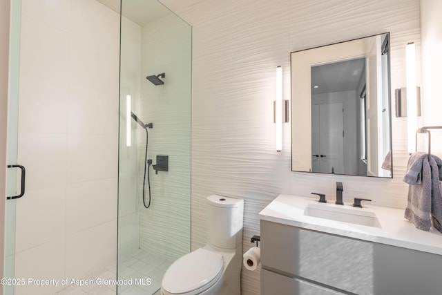 bathroom featuring toilet, tile walls, vanity, and a tile shower