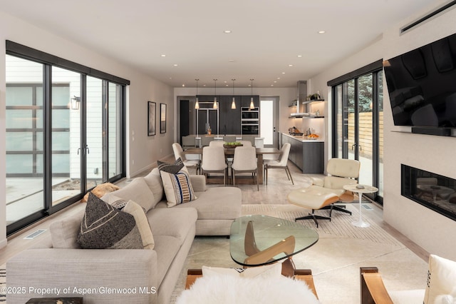 living area with recessed lighting, visible vents, baseboards, and a glass covered fireplace