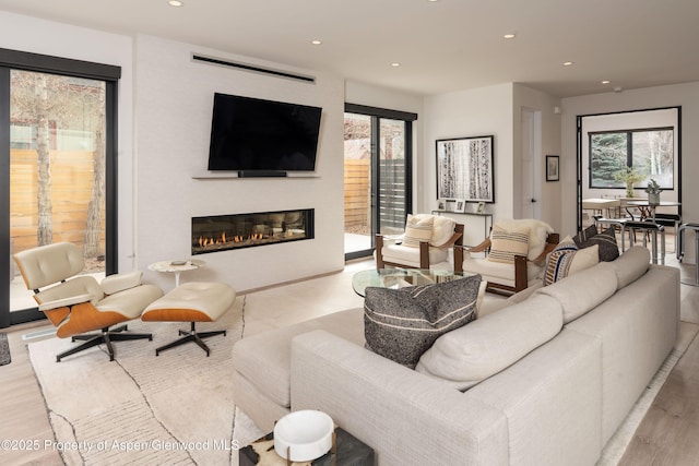 living area featuring recessed lighting, wood finished floors, and a glass covered fireplace