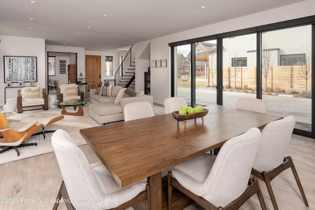 dining room featuring recessed lighting, light wood-style flooring, and stairs