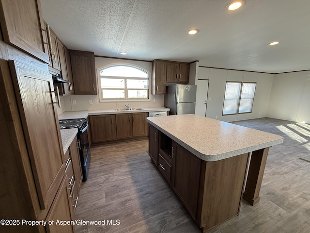 kitchen featuring sink, a center island, wood-type flooring, stainless steel refrigerator, and black range with electric cooktop