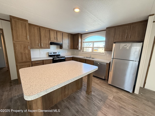 kitchen with a breakfast bar area, stainless steel appliances, a center island, a textured ceiling, and sink